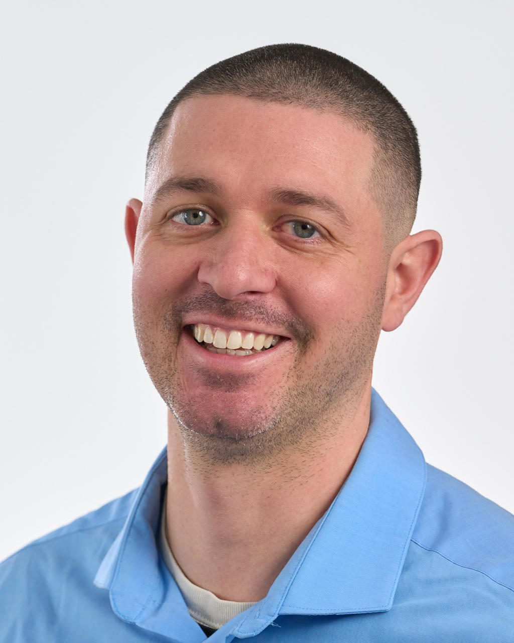 Smiling man in a blue shirt against a white background.