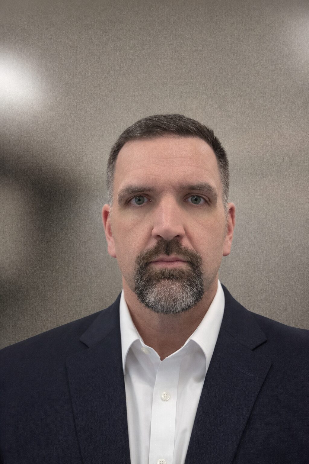 Professional headshot of a man in a suit with a neutral expression.