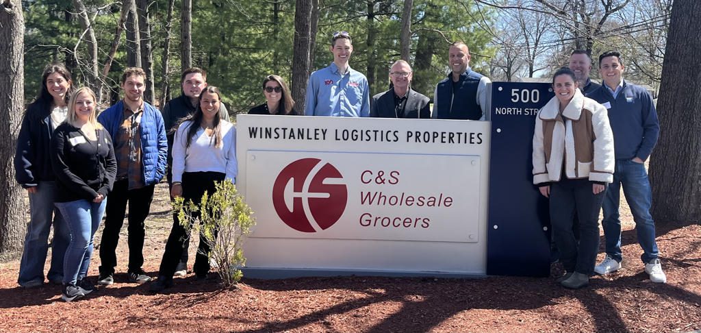 People standing near a Winstanley Logistics Properties sign outside.
